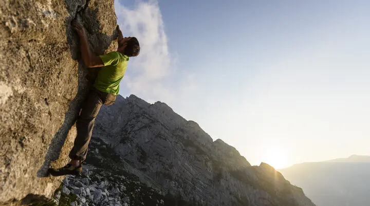 Ein Mann beim Bouldern am Fels im Sonnenuntergang | © DAV/Wolfgang Ehn